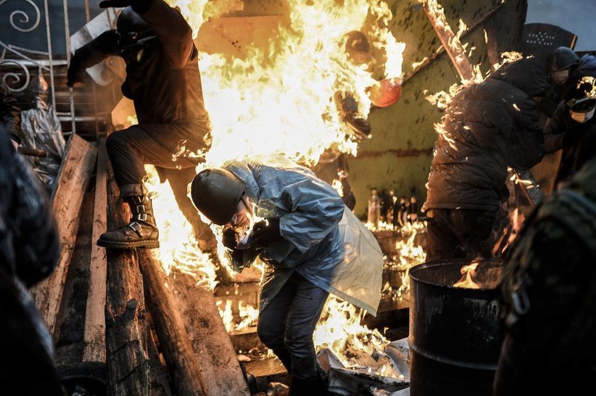 Φεβρουάριος: Διαδηλωτές που είχαν θωρακιστεί πισω από φλεγόμενα οχυρά, καίγονται, κατά τη διάρκεια επεισοδίων με την αστυνομία, στο Κίεβο