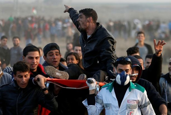 A wounded Palestinian shouts as he is evacuated during clashes with Israeli troops at a protest near