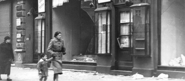 Mother and chiled passing by destroyed shop fronts. THe Wiener Library